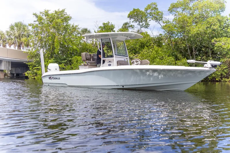 Slide: The Image of 2022 Crevalle 26 HBW boat on calm water, surrounded by lush greenery. - 18