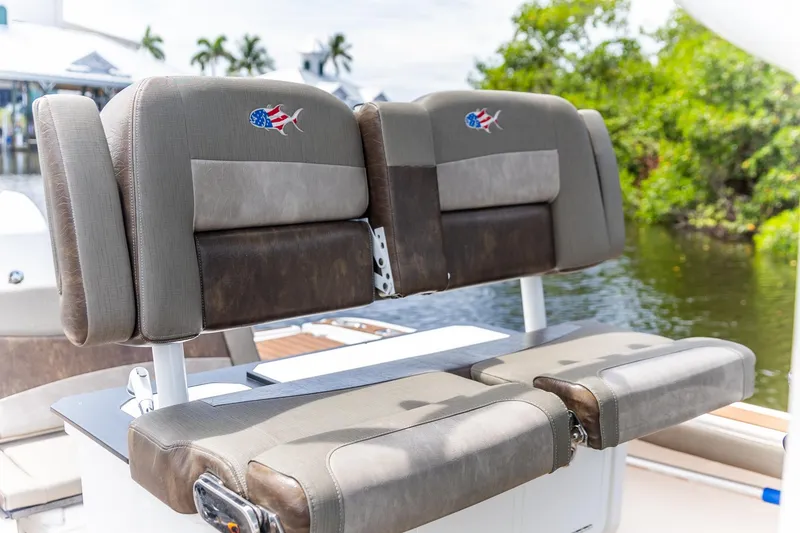 Slide: The Image of 2022 Crevalle 26 HBW boat seats with American flag fish logo, near water. - 2
