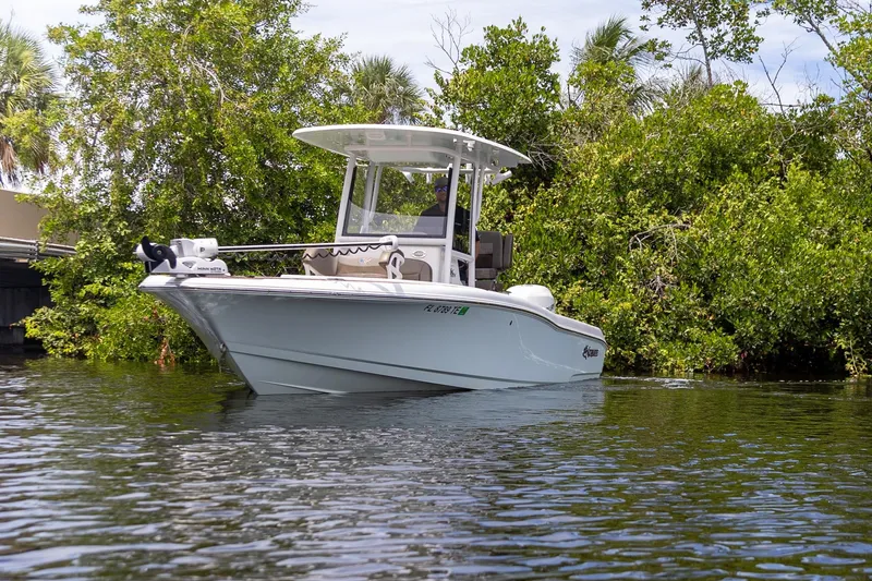 Slide: The Image of 2022 Crevalle 26 HBW boat on calm water near lush greenery. - 36