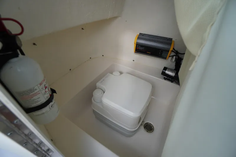 Slide: The Image of 2019 Tidewater 220 LXF boat interior with portable toilet and fire extinguisher. - 17