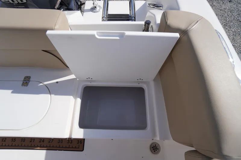 Slide: The Image of 2019 Tidewater 220 LXF boat storage compartment with beige seating and measuring ruler. - 44