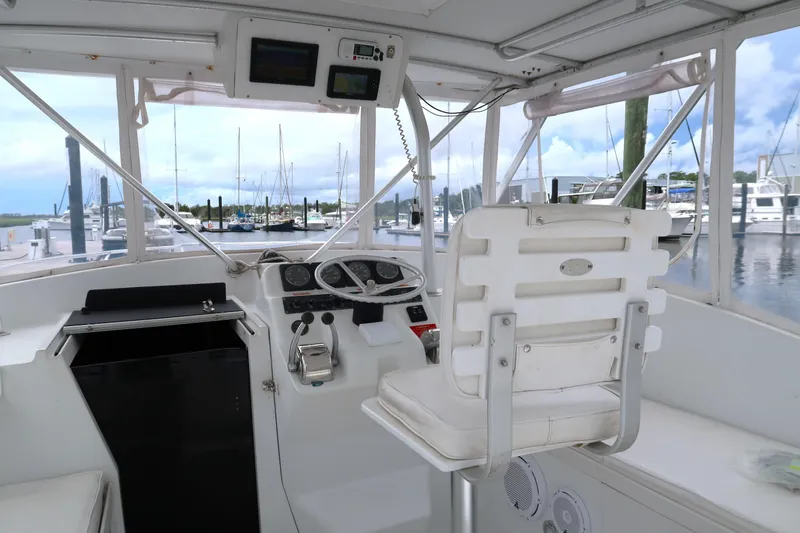 Slide: The Image of 1997 Luhrs Tournament 290 boat helm with marina view, featuring steering wheel and navigation equipment. - 13
