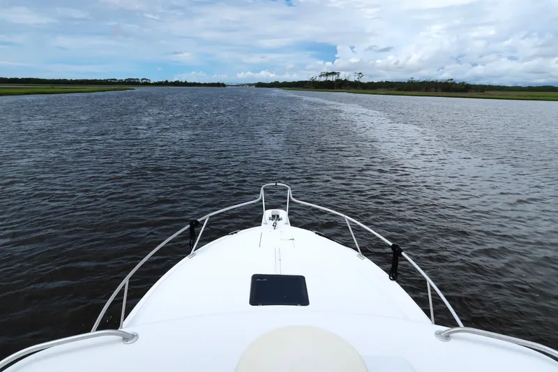 Slide: The Image of Bow view of 1997 Luhrs Tournament 290 cruising on a calm river under a cloudy sky. - 5