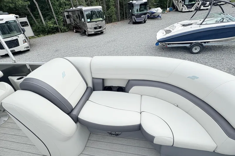 Slide: The Image of 2024 Starcraft 20 EX QDH pontoon boat with canopy, parked among RVs and boats. - 14