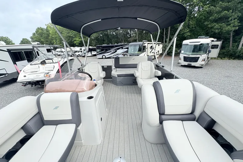 Slide: The Image of 2024 Starcraft 20 EX QDH pontoon boat with spacious seating and canopy in a parking area. - 15
