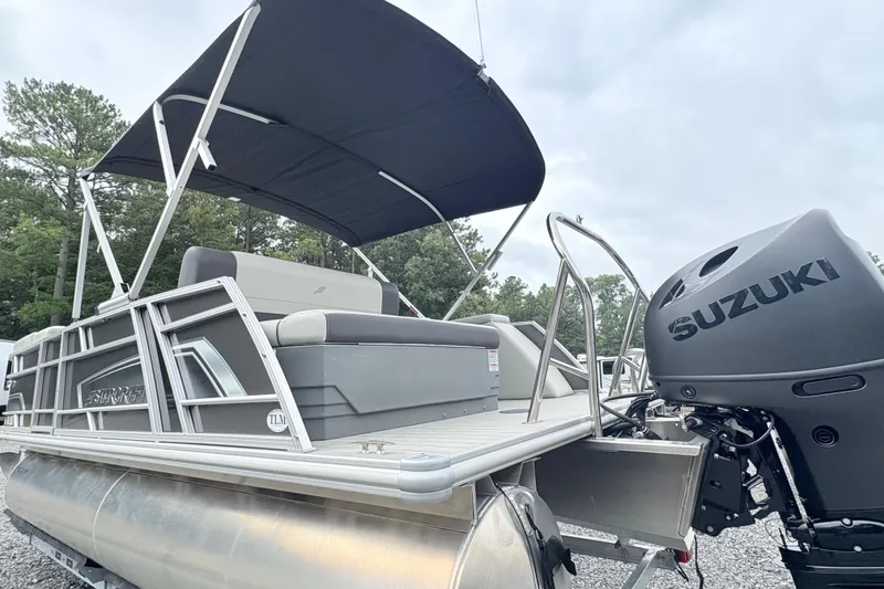 Slide: The Image of 2024 Starcraft 20 EX QDH pontoon boat with Suzuki outboard motor in a parking lot. - 5