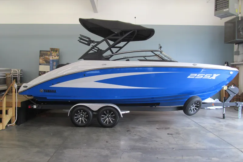 Slide: The Image of 2025 Yamaha Boats 255XD in showroom, blue and white design, on trailer. - 0