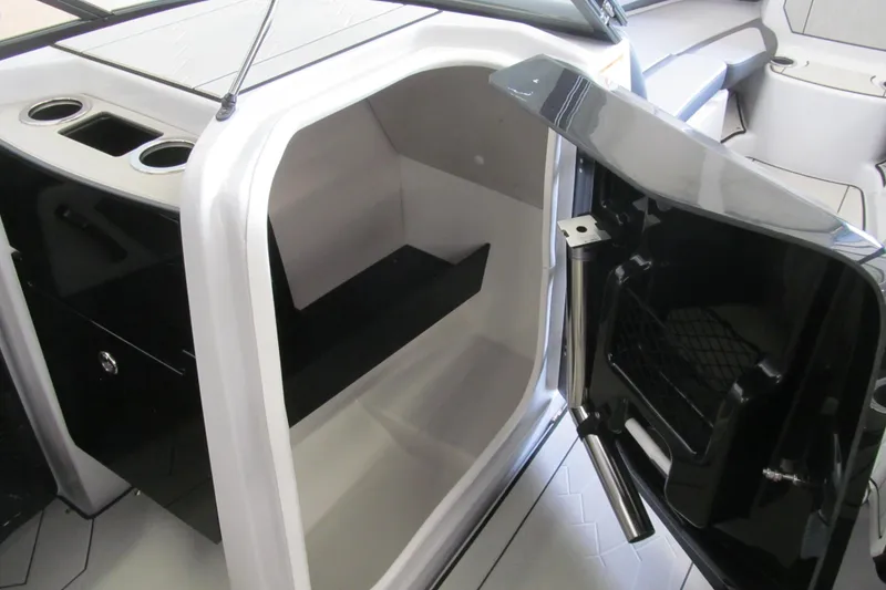Slide: The Image of 2025 Yamaha Boats 255XD interior storage compartment with open door and cup holders. - 7