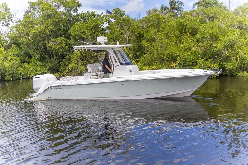 The Image of 2023 Edgewater 262CC boat cruising on a calm river, surrounded by lush greenery. - 0