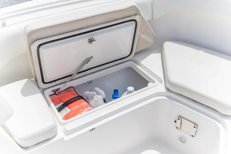 Slide: The Image of 2023 Edgewater 262CC boat storage compartment with safety gear and supplies. - 12