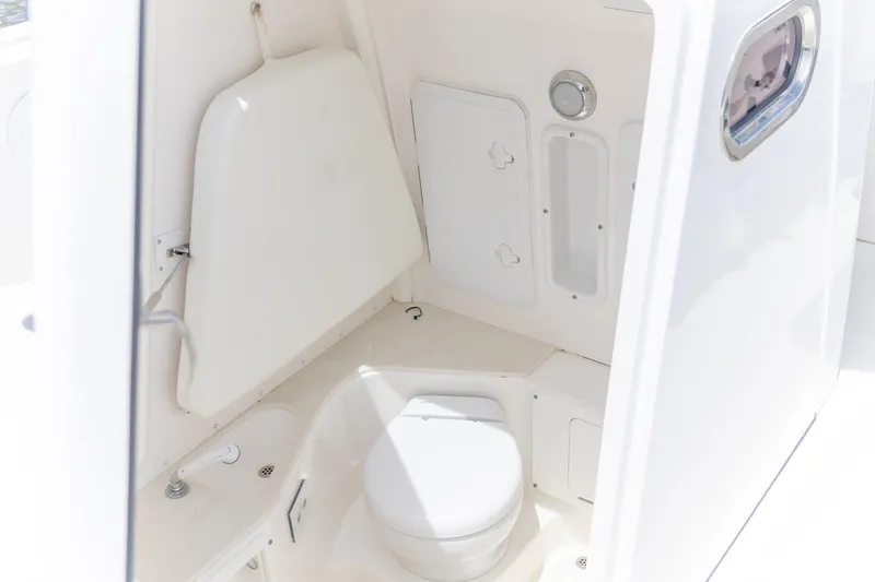 Slide: The Image of 2023 Edgewater 262CC boat interior with compact marine toilet and storage. - 2