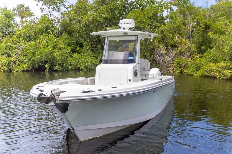 Slide: The Image of 2023 Edgewater 262CC boat cruising on a calm river with lush greenery. - 24