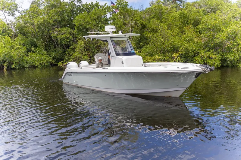 Slide: The Image of 2023 Edgewater 262CC boat cruising on a calm river with lush greenery. - 26