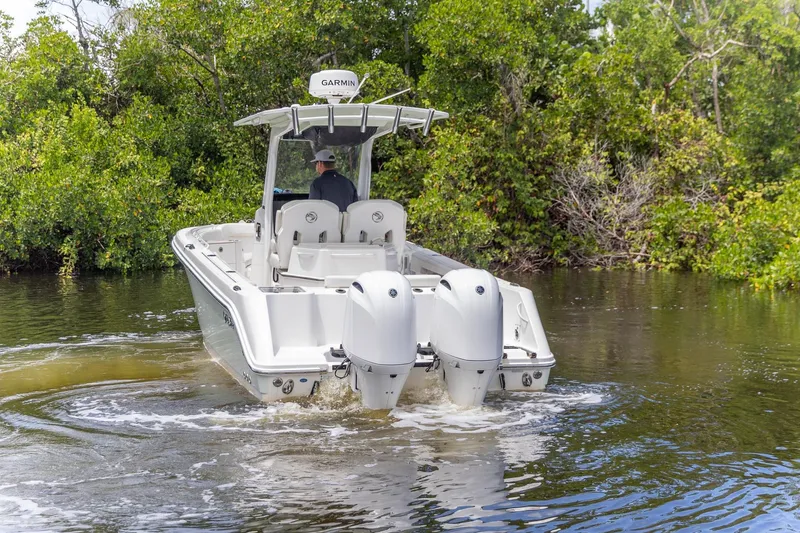 Slide: The Image of 2023 Edgewater 262CC boat navigating through calm waters near lush greenery. - 28