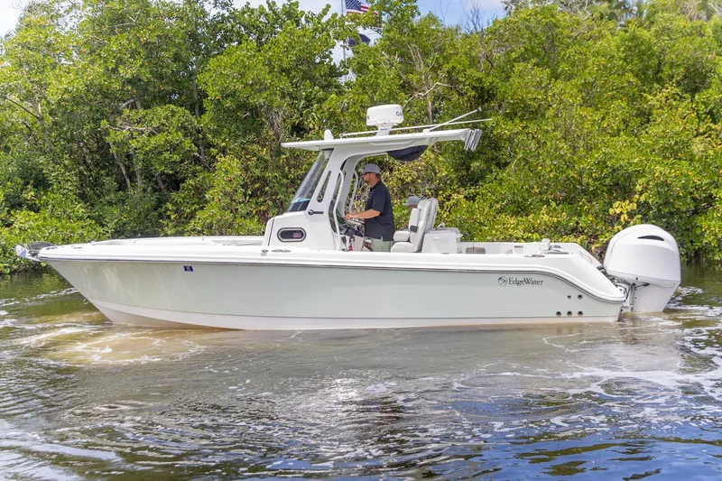 Slide: The Image of 2023 Edgewater 262CC boat cruising on a calm river, surrounded by lush greenery. - 30