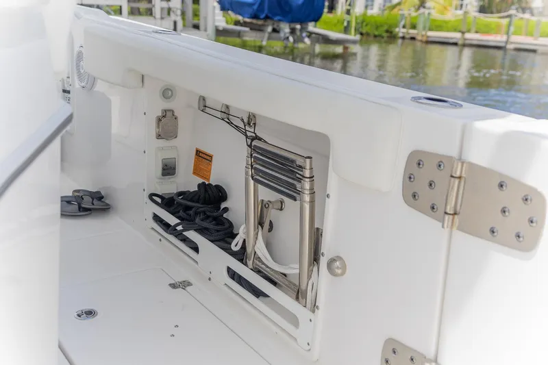 Slide: The Image of 2023 Edgewater 262CC boat storage compartment with ladder and ropes by the water. - 33