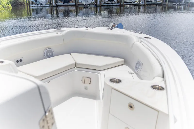 Slide: The Image of 2023 Edgewater 262CC boat interior with cushioned seating and cup holders by the water. - 8
