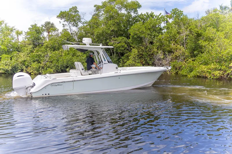 Slide: The Image of 2023 Edgewater 262CC boat cruising on a serene waterway surrounded by lush greenery. - 9