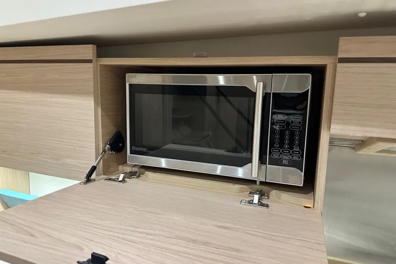 Slide: The Image of Microwave in Beneteau Oceanis 55.1 yacht kitchen, 2021 model, with wooden cabinetry. - 49