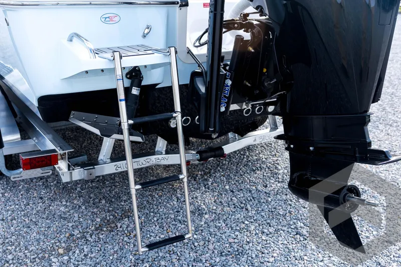 Slide: The Image of Tidewater 2410 Bay Max 2026 boat with ladder and motor on gravel. - 21