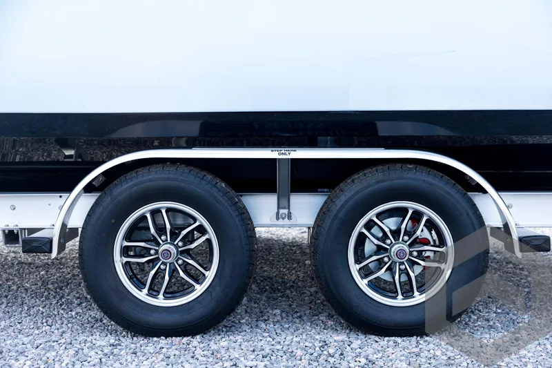 Slide: The Image of 2026 Tidewater 2410 Bay Max trailer wheels on gravel surface. - 28