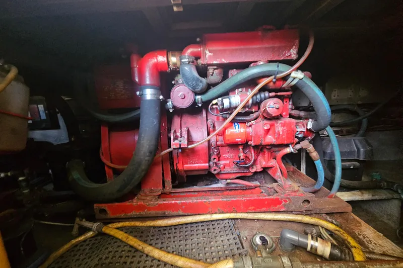 Slide: The Image of Engine compartment of a 1986 Viking 35 Convertible boat, featuring red machinery and hoses. - 13