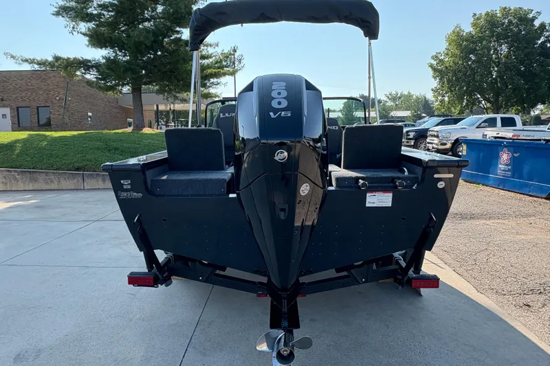 Slide: The Image of 2026 Lund 1875 Pro-V Sport boat with powerful 200 V6 engine, parked outdoors. - 2