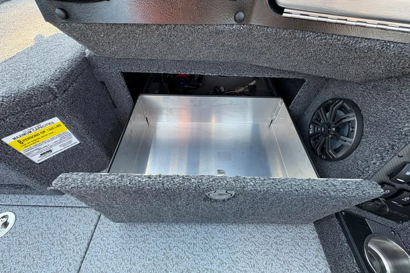 Slide: The Image of 2026 Lund 1875 Pro-V Sport boat storage compartment with speaker and capacity label. - 22