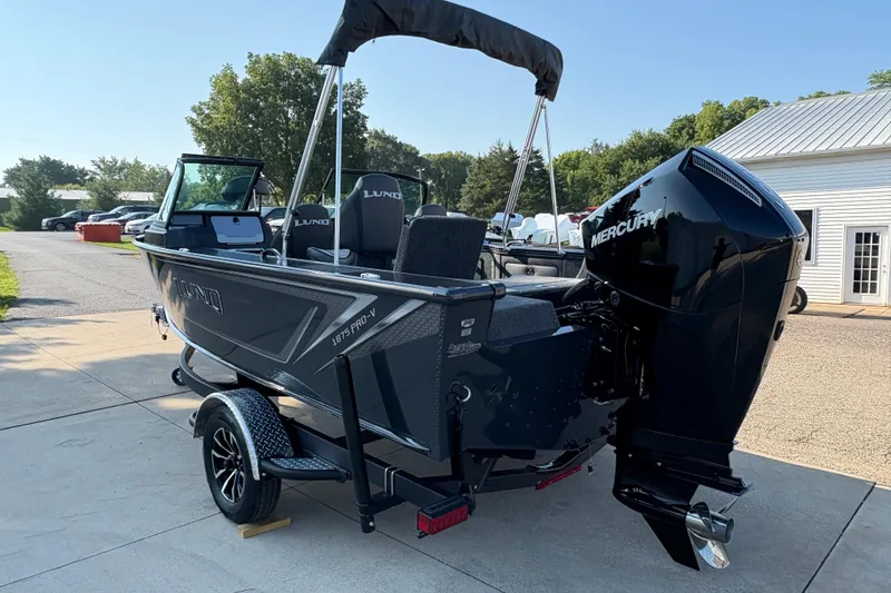 Slide: The Image of 2026 Lund 1875 Pro-V Sport boat with Mercury engine on a trailer, parked outdoors. - 3