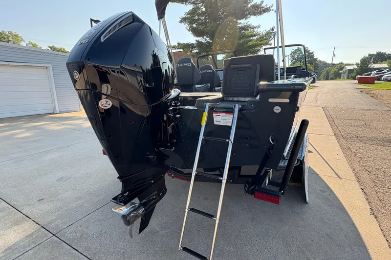 Slide: The Image of 2026 Lund 1875 Pro-V Sport boat with powerful outboard motor and ladder, parked on driveway. - 37