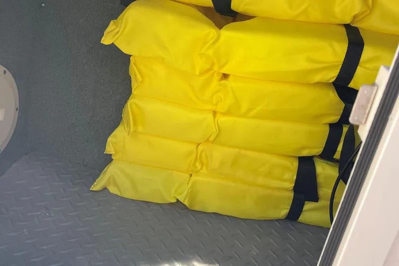 Slide: The Image of Stacked yellow life jackets in a 2014 Grady-White Freedom 225 boat compartment. - 17