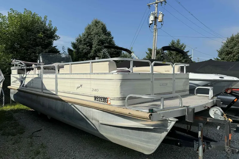 Slide: The Image of 1997 Lowe 240 Family pontoon boat parked on gravel, surrounded by trees and power lines. - 13