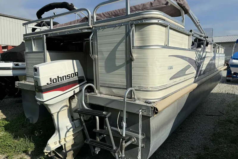 Slide: The Image of 1997 Lowe 240 Family pontoon boat with Johnson outboard motor, parked on gravel. - 3