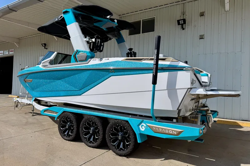Slide: The Image of 2021 Nautique Super Air Nautique G23 Paragon boat on trailer, vibrant blue and white design. - 2