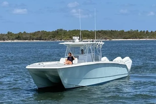 Slide: The Image of Invincible 40 Catamaran 2020 on water, person relaxing on deck, scenic background. - 1