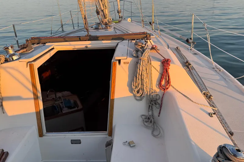 Slide: The Image of 1994 Catalina 320 sailboat deck with ropes and open cabin entrance at sunset. - 10