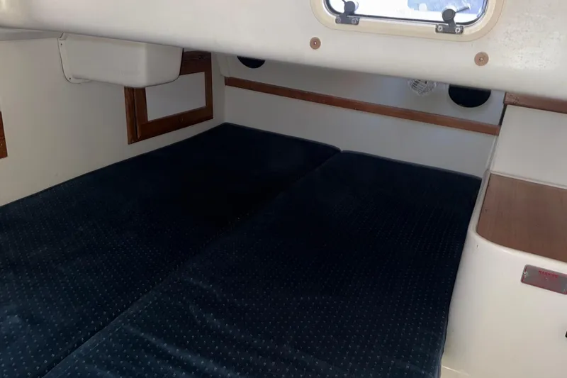 Slide: The Image of Interior cabin of a 1994 Catalina 320 sailboat with dark cushions and wooden accents. - 16