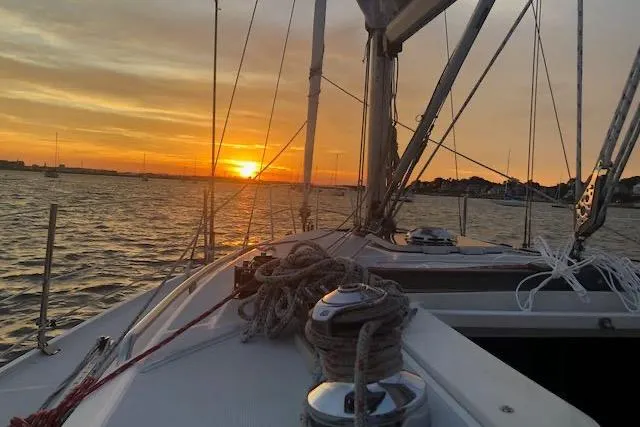Slide: The Image of Sailing on a 1994 Catalina 320 at sunset, with vibrant orange sky and calm waters. - 2