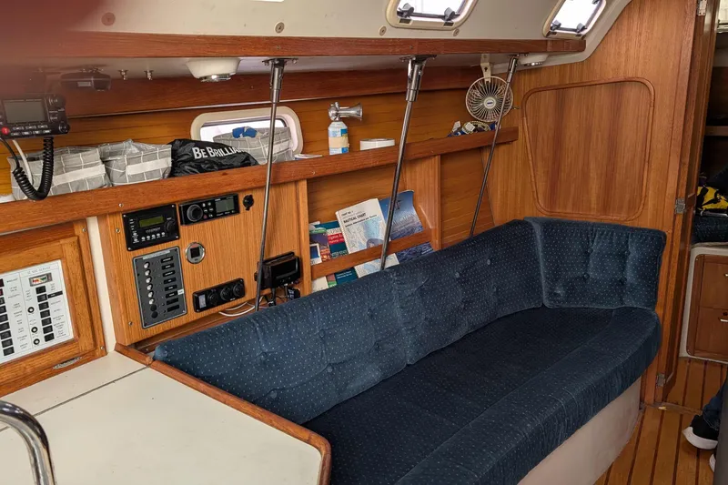 Slide: The Image of Interior of a 1994 Catalina 320 sailboat with blue cushioned seating and wooden paneling. - 4