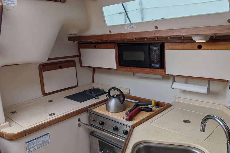 Slide: The Image of Interior of a 1994 Catalina 320 sailboat kitchen with stove, microwave, and sink. - 7