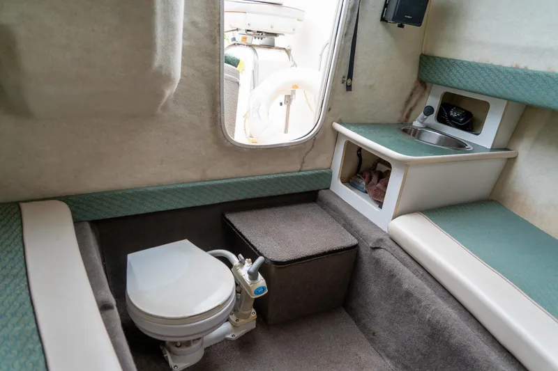 Slide: The Image of 2002 Bayliner 2302 Trophy Walkaround cabin with toilet, sink, and seating area. - 24