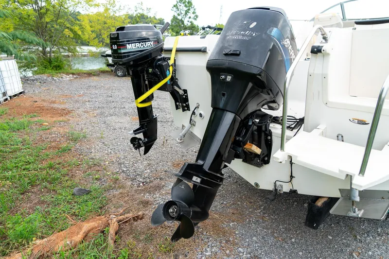 Slide: The Image of 2002 Bayliner 2302 Trophy Walkaround with dual Mercury outboard motors on a gravel surface. - 7