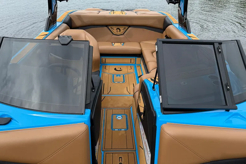 Slide: The Image of 2025 Centurion Nv233 boat interior with tan seating and blue accents on the water. - 17