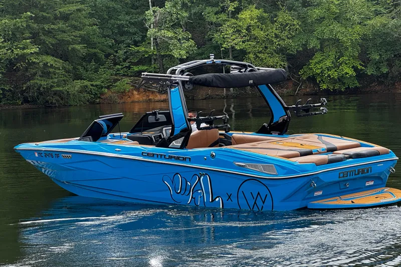 Slide: The Image of 2025 Centurion Nv233 boat in vibrant blue on a serene lake. - 2