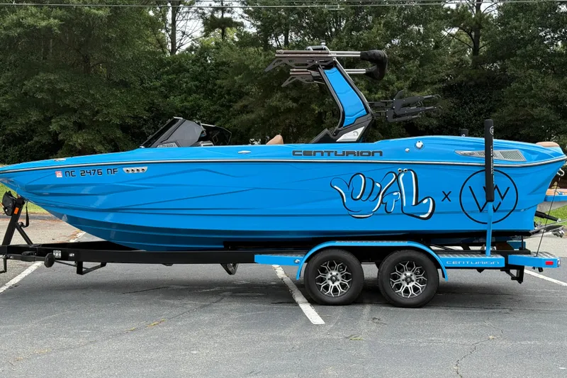Slide: The Image of 2025 Centurion Nv233 boat in vibrant blue with custom graphics on a trailer. - 23