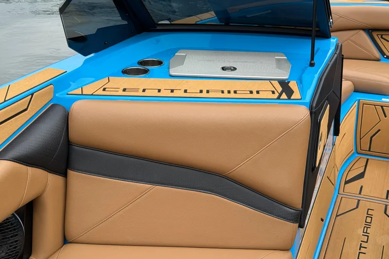 Slide: The Image of 2025 Centurion Nv233 boat interior with tan and black seating, blue accents, and branded details. - 7