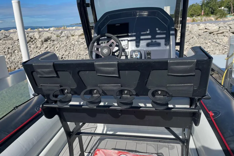 Slide: The Image of 2019 Zodiac Open 7 boat cockpit with steering wheel and control panel, docked by rocky shore. - 14