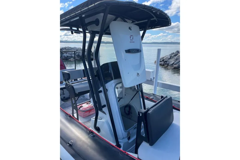 Slide: The Image of 2019 Zodiac Open 7 boat with console, docked by rocky shoreline. - 9