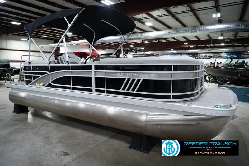 Slide: The Image of 2023 Bennington 22 LSR pontoon boat in showroom, featuring sleek design and canopy. - 5