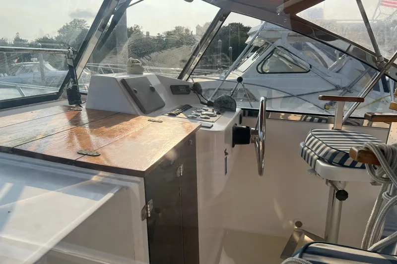 Slide: The Image of 2005 Legacy Yachts 28 cockpit with wooden dashboard and striped seating. - 6